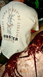 Josh wearing the Mutiny Lobster Gauge Tee, in tan, standing in front of a couple lobsters that were hauled in.